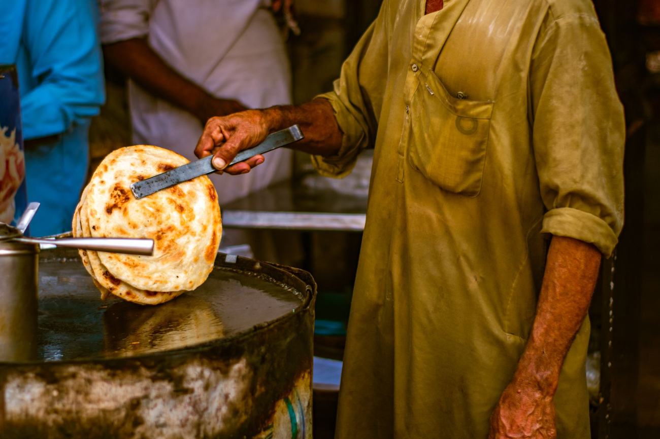A street vendor flipping paratha on a tawa